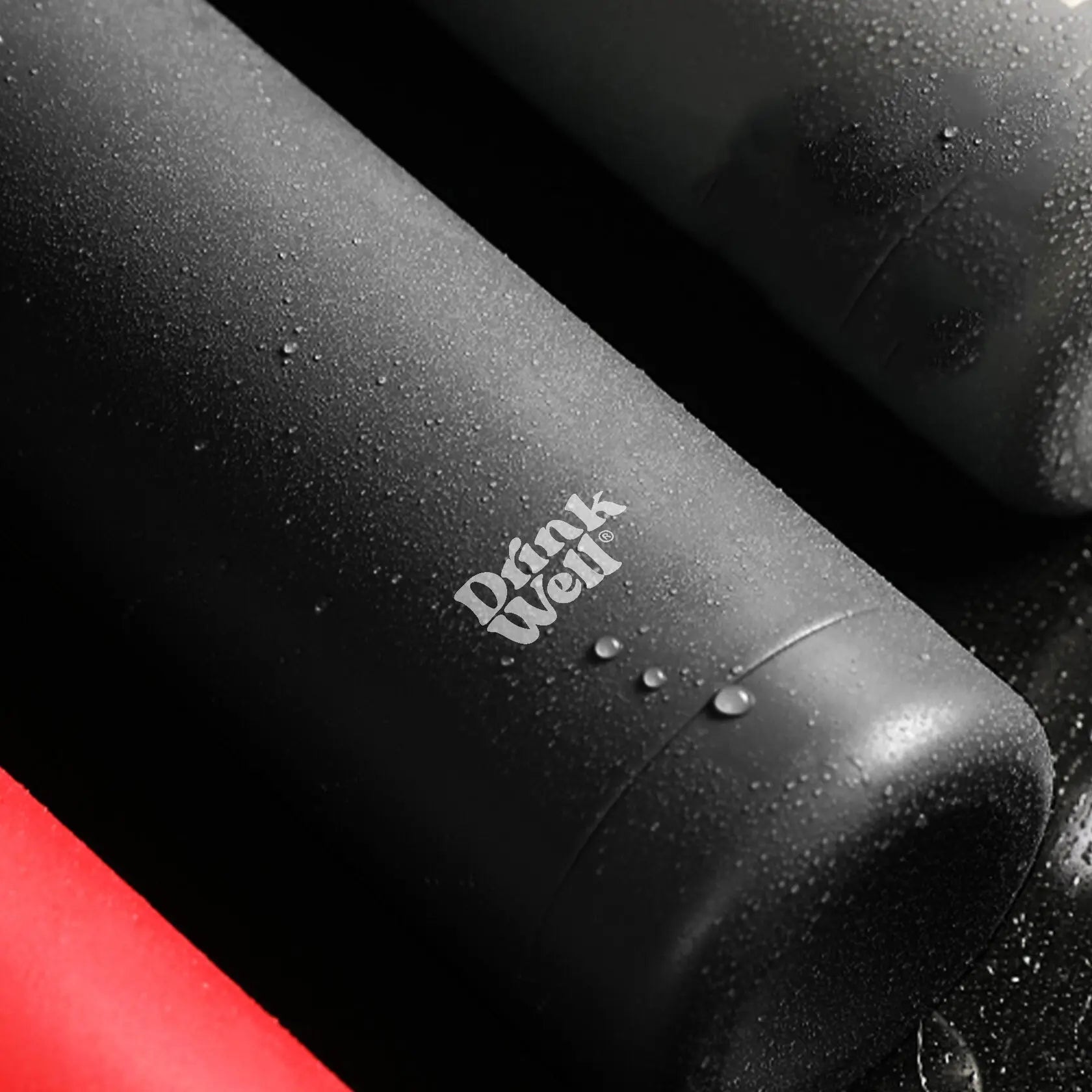 Zoom sur la bouteille en inox noire DrinkWell avec finition antidérapante et effet de condensation.