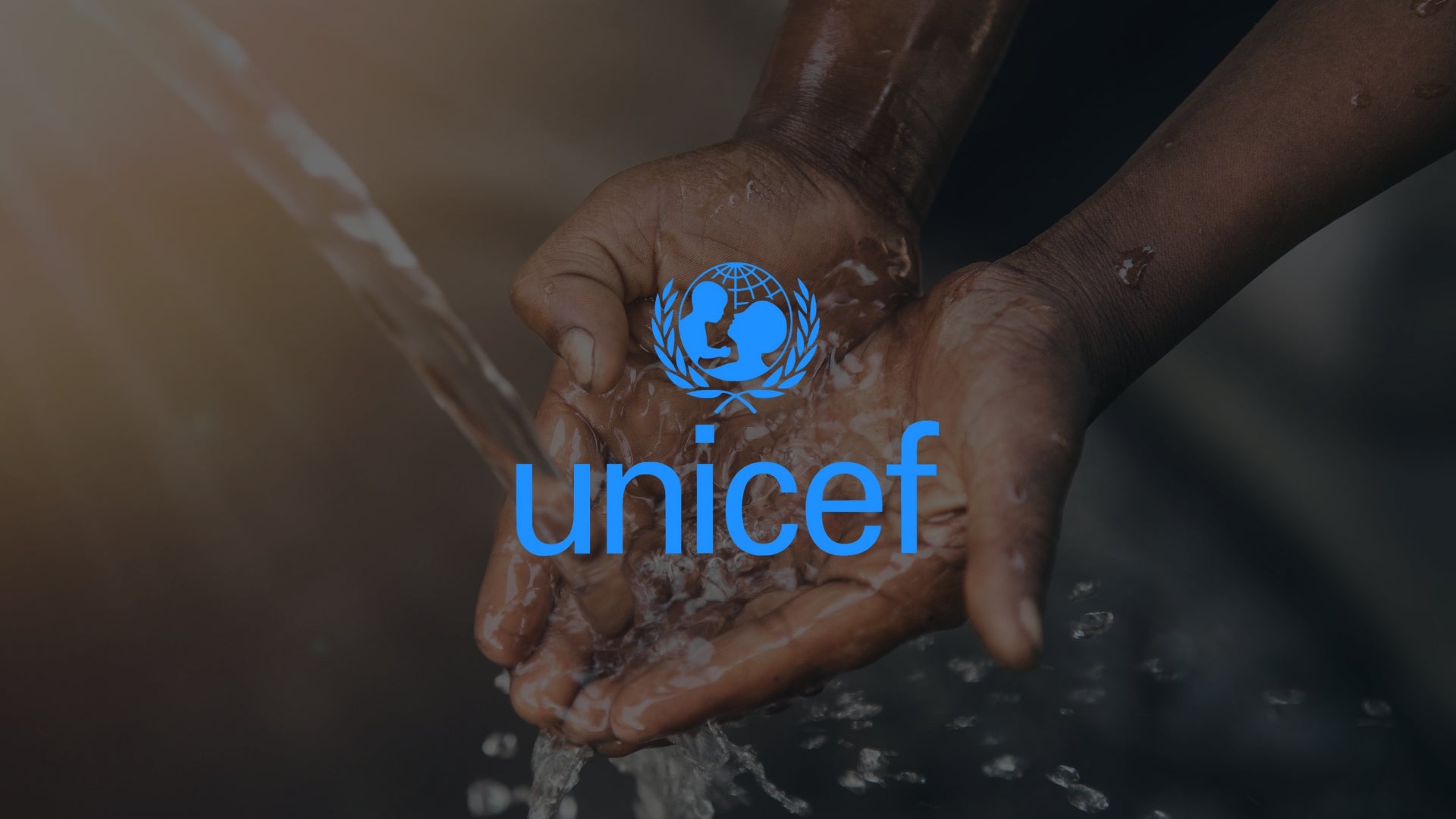 Mains d’enfant recueillant de l’eau sous un robinet, avec le logo UNICEF, illustrant l’engagement solidaire de DrinkWell : 1€ reversé par gourde achetée.