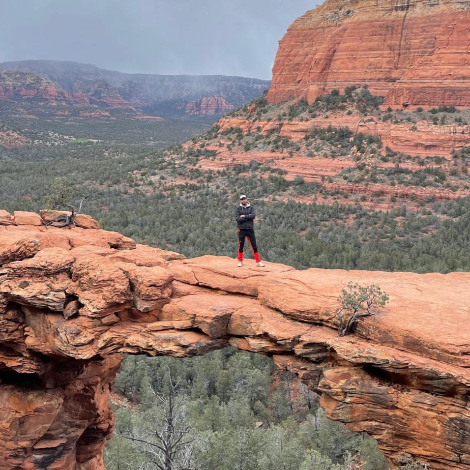 Pierre Rizk, cofondateur de DrinkWell, debout sur une arche rocheuse à Sedona, incarnant l’esprit d’aventure, de performance et d’innovation de la marque.